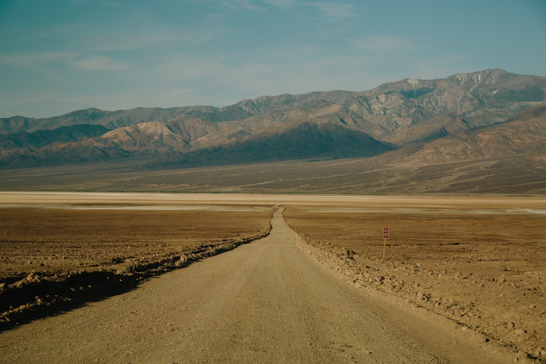 Empty gravel road running toward distant mountains